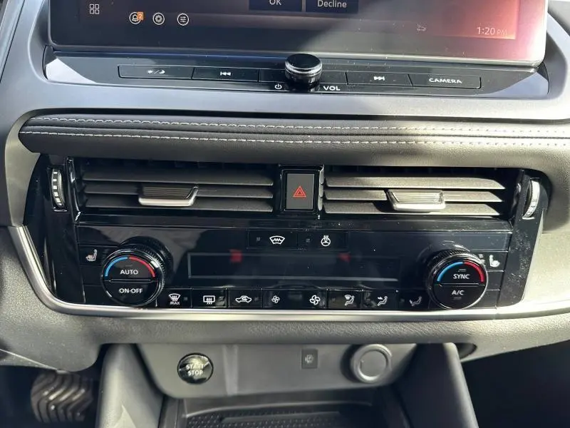 Vue rapprochée du tableau de bord du Nissan Qashqai Hybrid e-POWER 2025, avec commandes climatisation et bouton start/stop.
