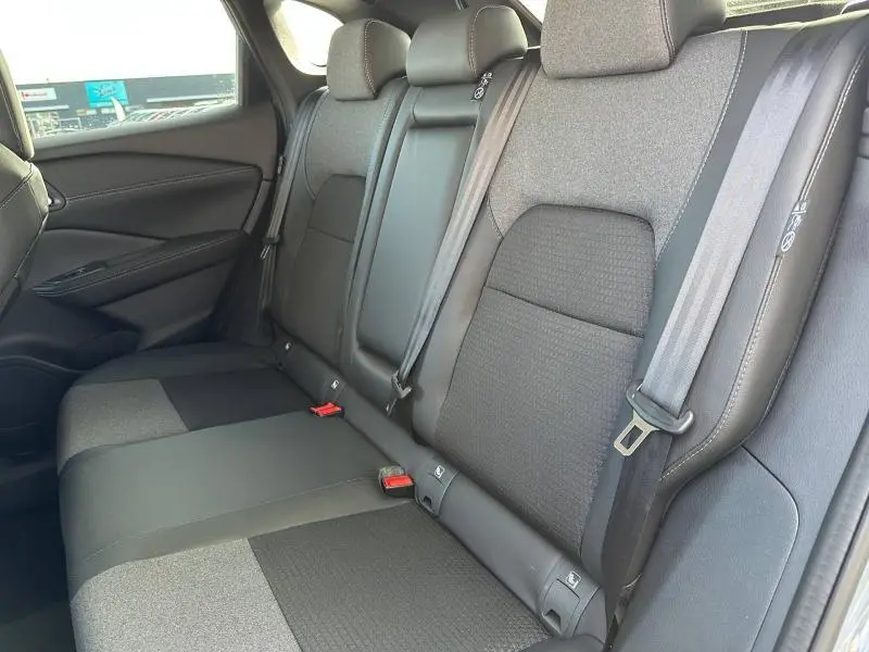 Vue intérieure du siège arrière droit du Nissan Qashqai Hybrid e-POWER 2025 en tissu gris avec ceinture de sécurité visible.