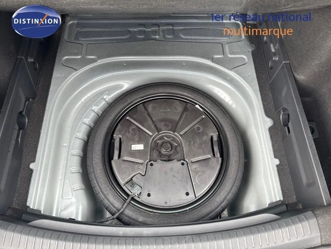 Vue plongeante sur la roue de secours dans le coffre d'une CUPRA Leon ST gris 2024, espace de rangement visible.