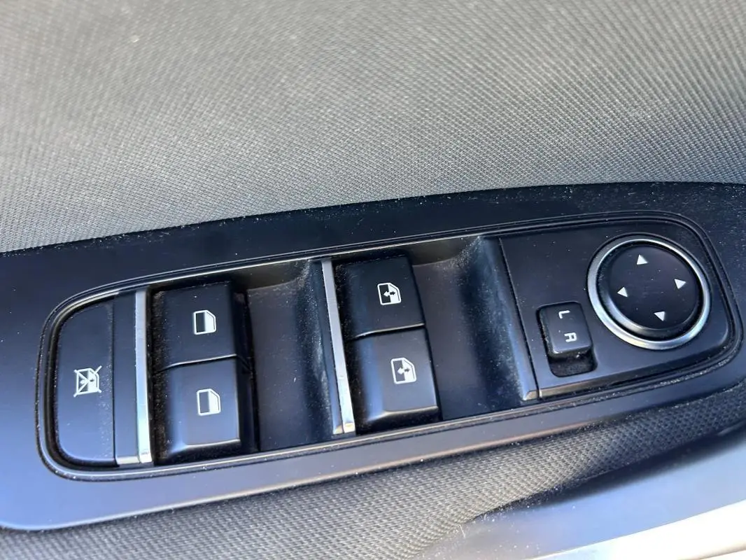 Gros plan sur les commandes des vitres électriques et rétroviseurs réglables côté conducteur d’une KIA CEE'D gris 2022.