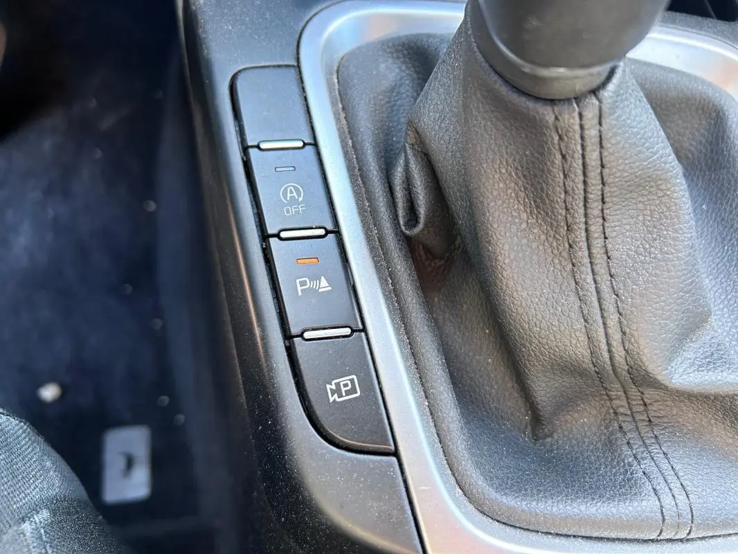 Gros plan sur la console centrale grise de la KIA CEE'D 2022 avec levier de vitesse manuel et boutons de contrôle.