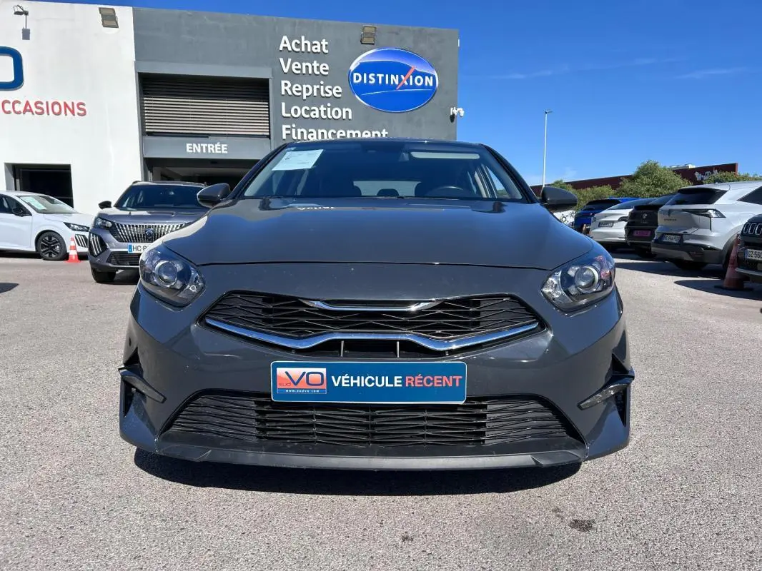 Vue frontale d'une KIA CEE'D gris 2022 avec calandre noire et plaque "Véhicule récent" en concession.