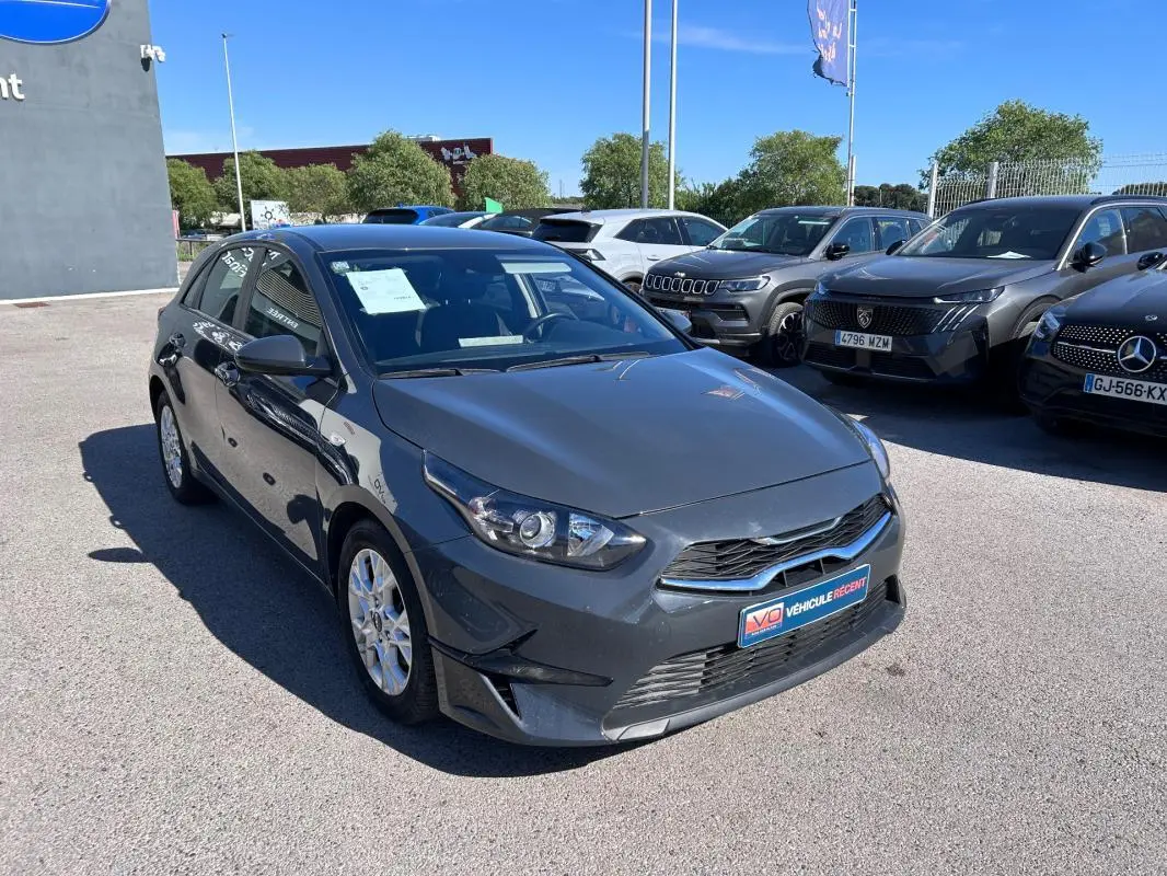 KIA CEE'D gris vue 3/4 avant droit, avec jantes 16 pouces et calandre noire brillante.