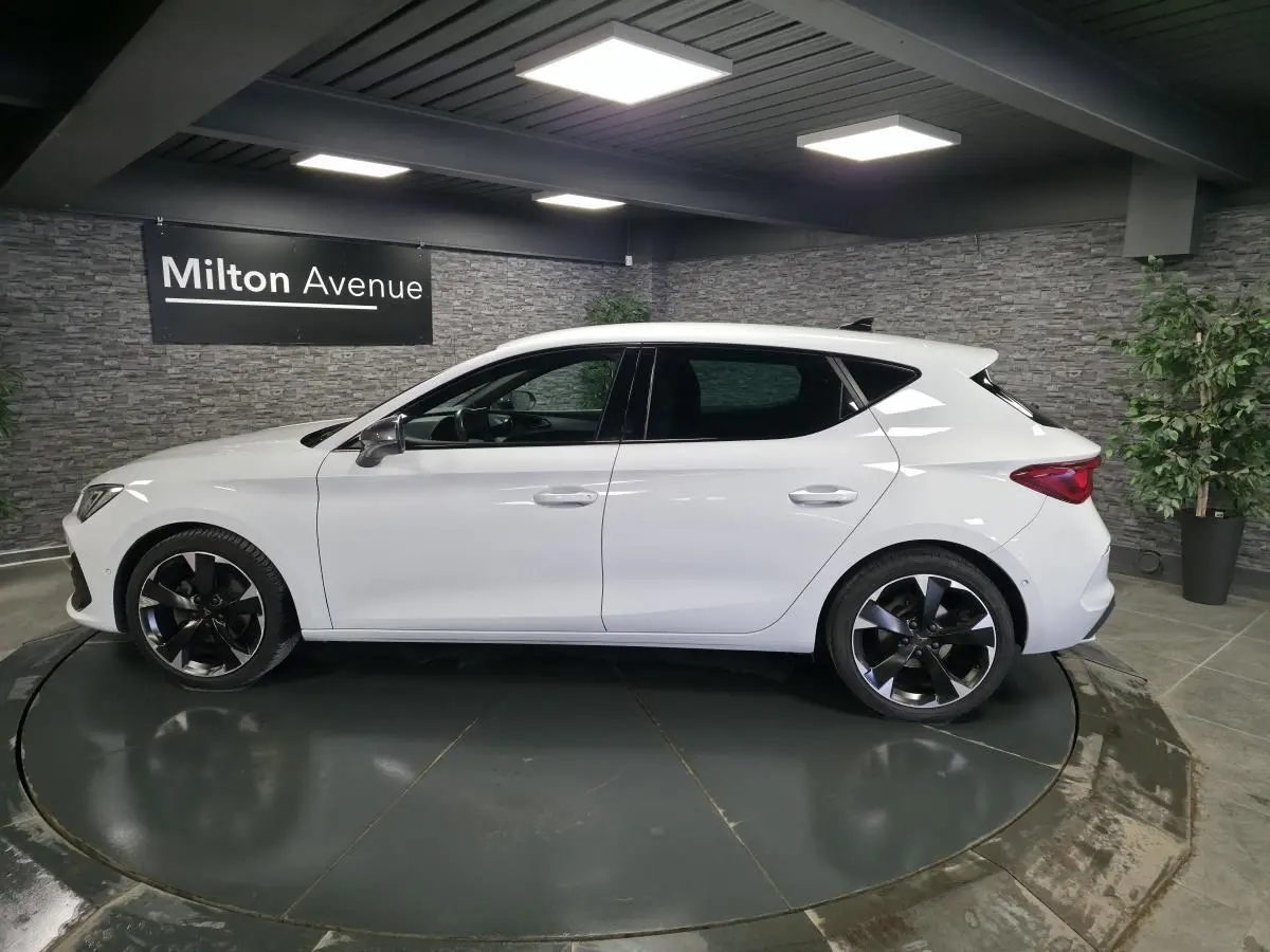 Vue latérale droite d'une CUPRA Leon blanche Nevada 2023 avec jantes alliage 18 pouces et vitres teintées.