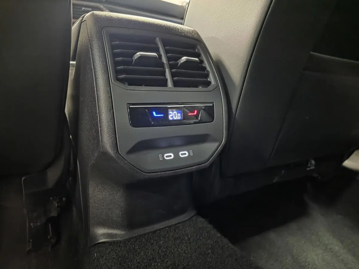 Vue rapprochée de la console arrière noire avec ventilation, réglage de climatisation à 20°C et deux prises USB-C éclairées.