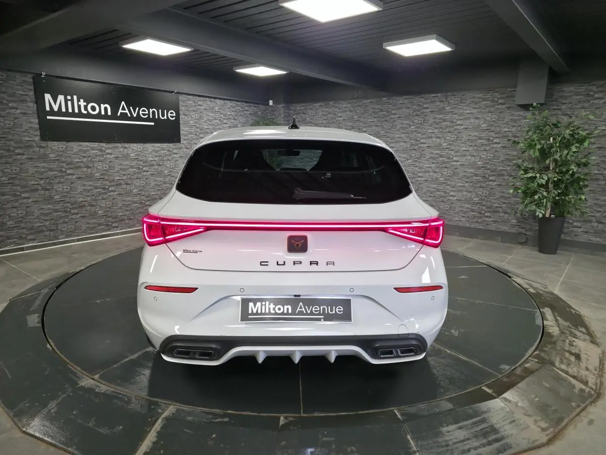 Vue arrière d'une CUPRA Leon blanche Nevada 2023 avec feux LED bandeau Infinite Light et double sortie d'échappement.