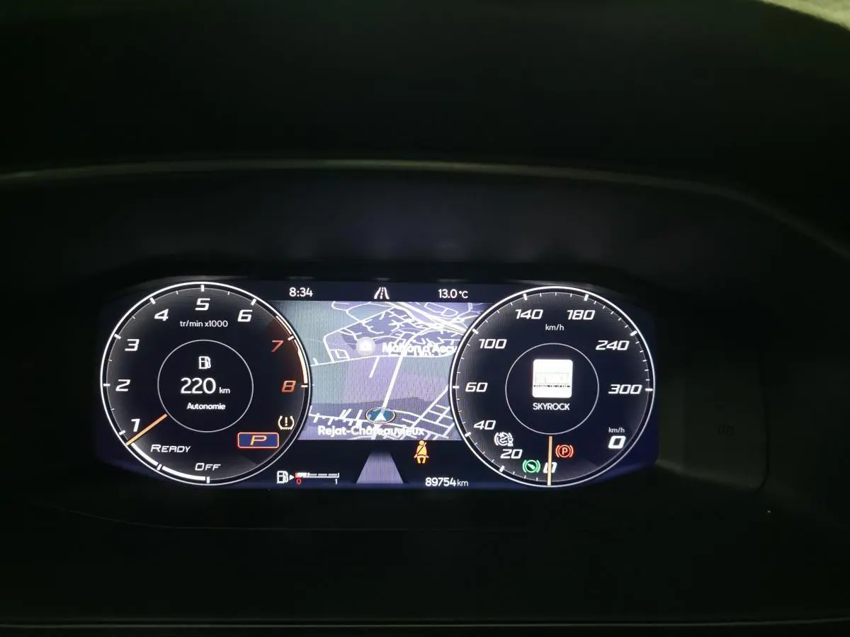 Combiné d'instruments digital de la CUPRA Leon 2023 affichant la navigation et l'autonomie essence hybride à 220 km.