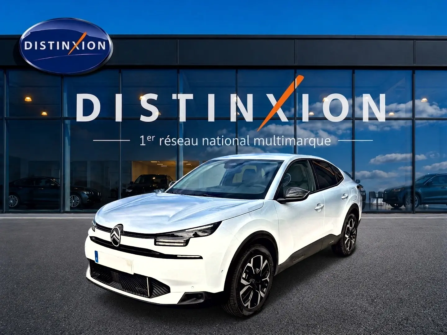Vue 3/4 avant d'une Citroën C4 X blanche avec jantes alu noires devant une vitrine Distinxion.
