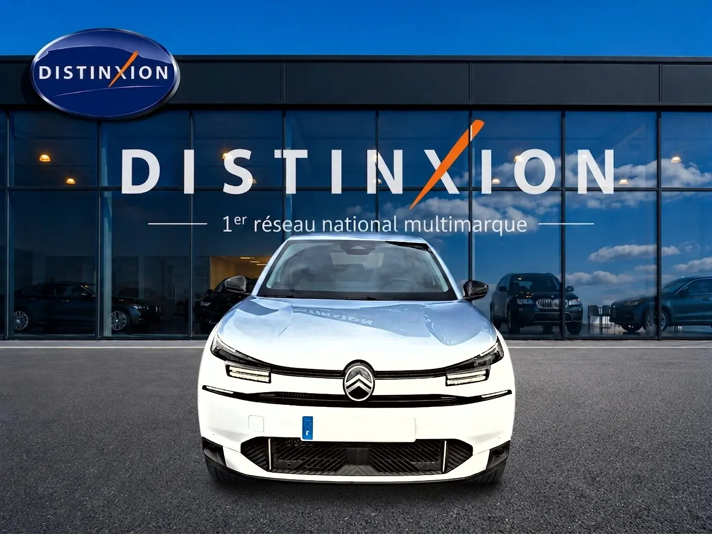 Vue frontale d'une Citroën C4 X blanche 2025 avec phares LED et calandre noire devant un bâtiment Distinxion.