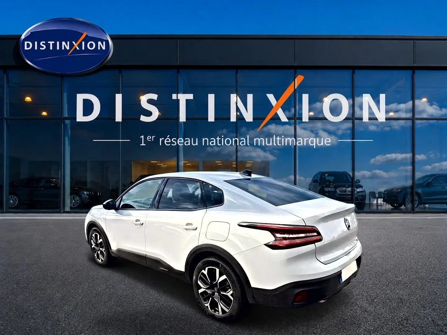 Vue 3/4 arrière droite d'une Citroën C4 X blanche 2025 avec feux arrière LED et jantes alu noires et argentées.