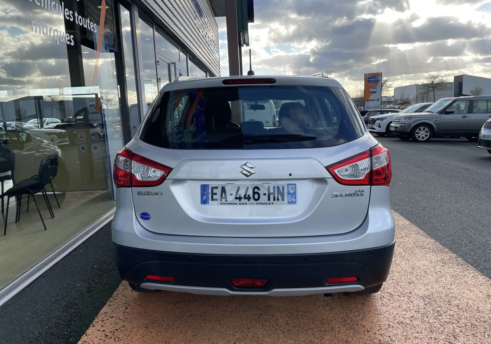 Vue arrière d'un Suzuki SX4 S-Cross gris métallisé 2016, avec feux arrière distinctifs et plaque d'immatriculation française.
