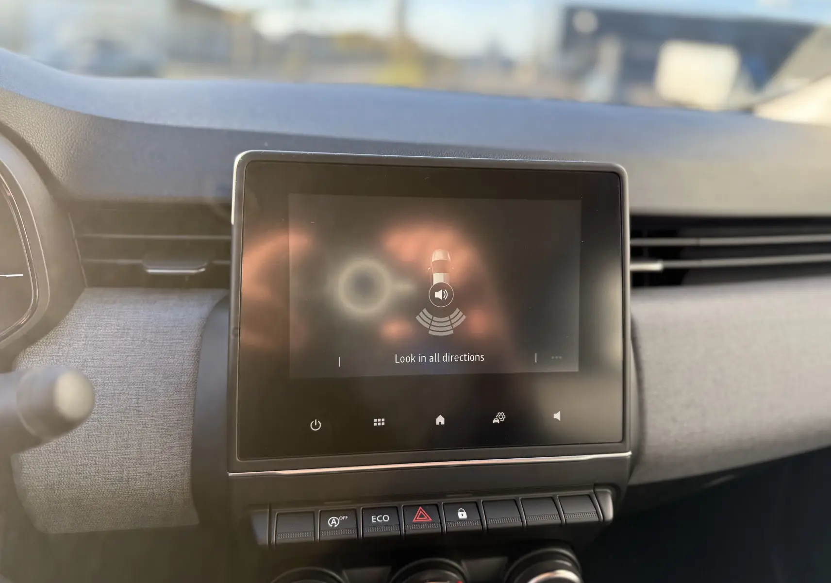 Écran tactile central du tableau de bord de la Renault Clio V gris schiste, avec commandes clim manuelle et mode eco visibles.