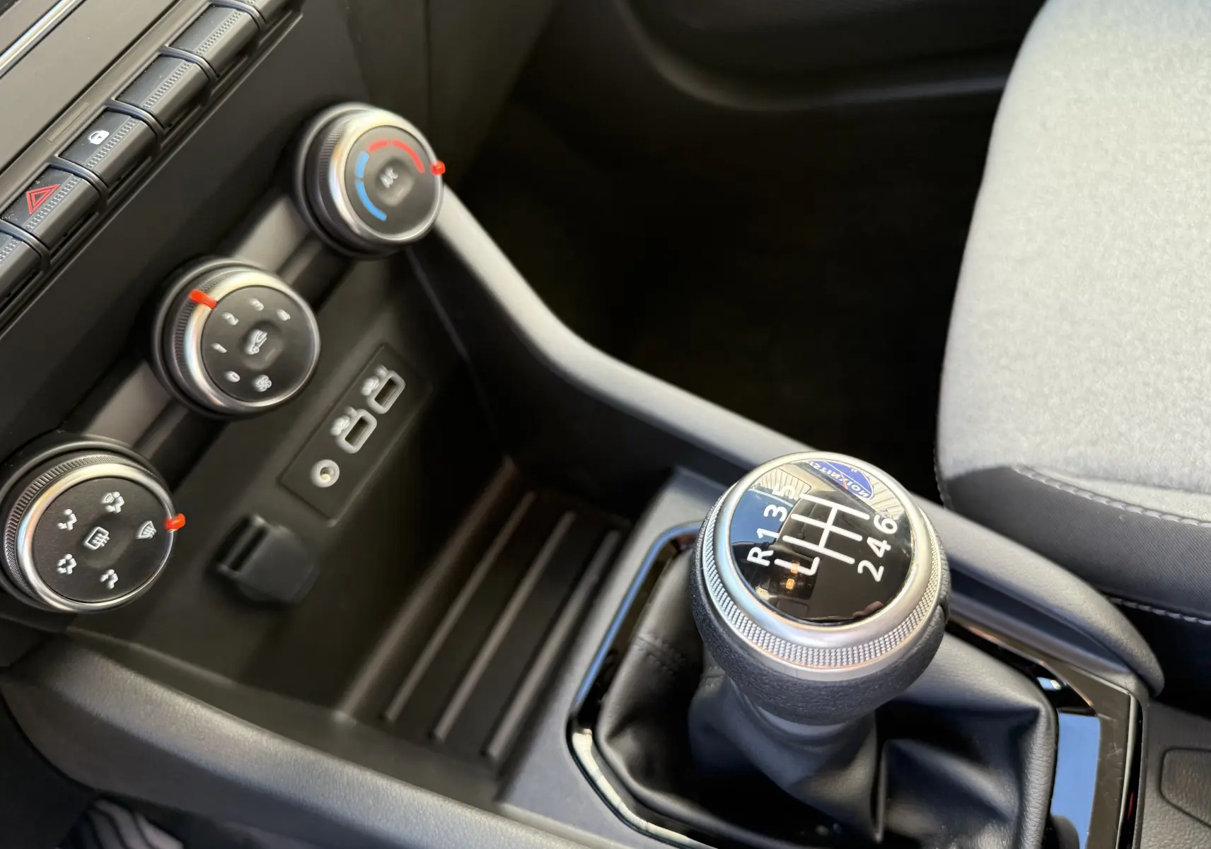 Gros plan sur la commande de boîte manuelle et les réglages de climatisation de la Renault Clio V gris schiste.