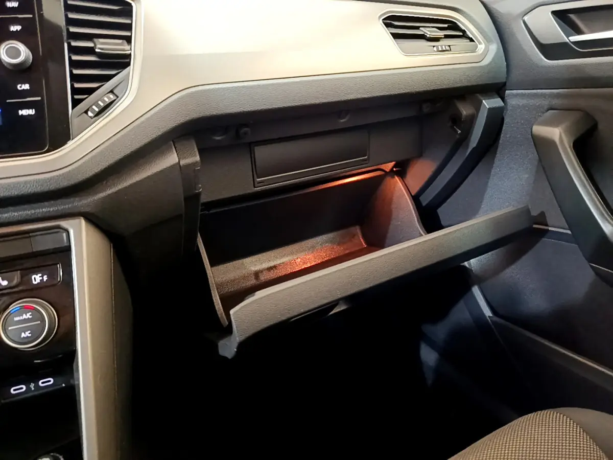 Gros plan de la boîte à gants ouverte côté passager dans l'habitacle sombre du Volkswagen T-Roc 2021.