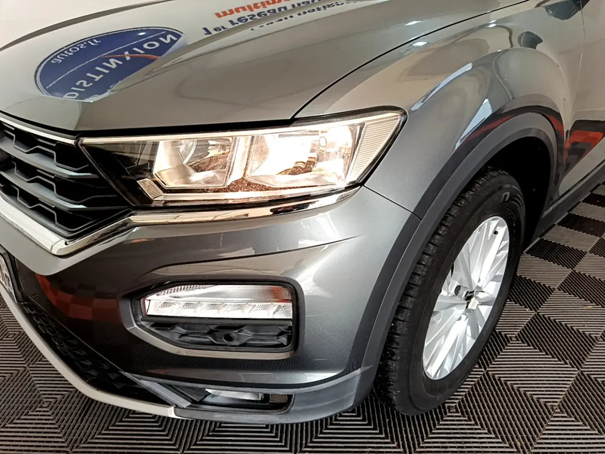 Gros plan sur l'avant droit gris foncé du Volkswagen T-Roc 2021 avec phares allumés et jante alu visible.