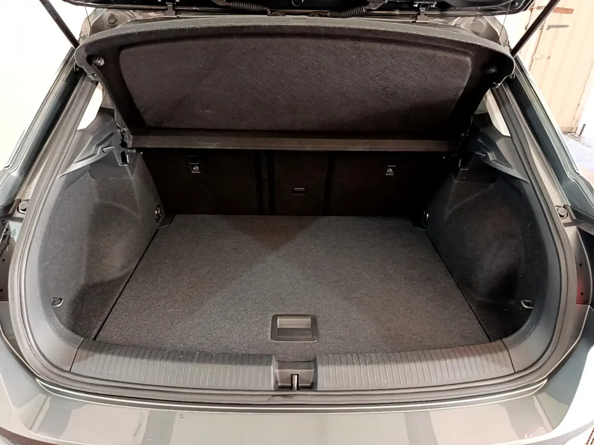 Coffre ouvert vu de l'arrière d'un Volkswagen T-Roc gris foncé, espace de chargement propre et spacieux.