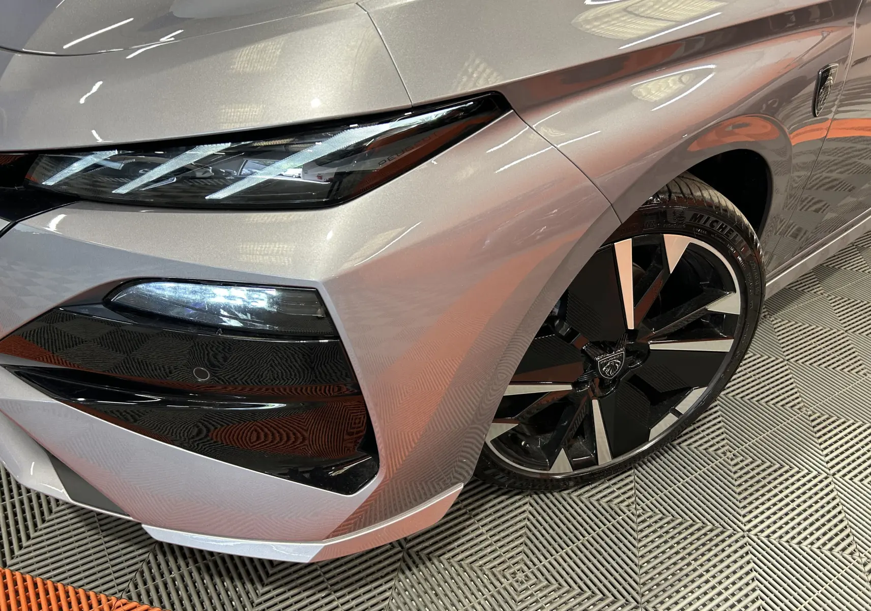 Gros plan sur l’avant droit gris Artense du Peugeot 308 III Ph.2 GT avec phares LED et jante noire et argent.