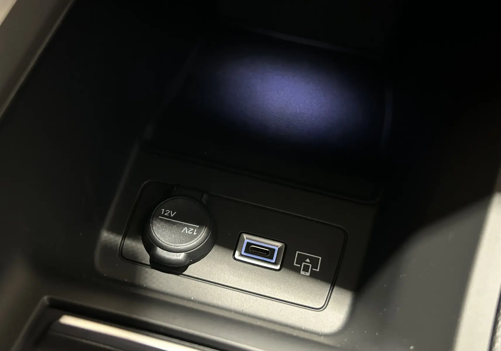 Gros plan intérieur sur la prise 12V et port USB-C du Peugeot 308 III Ph.2 GT Gris Artense, éclairage tamisé.