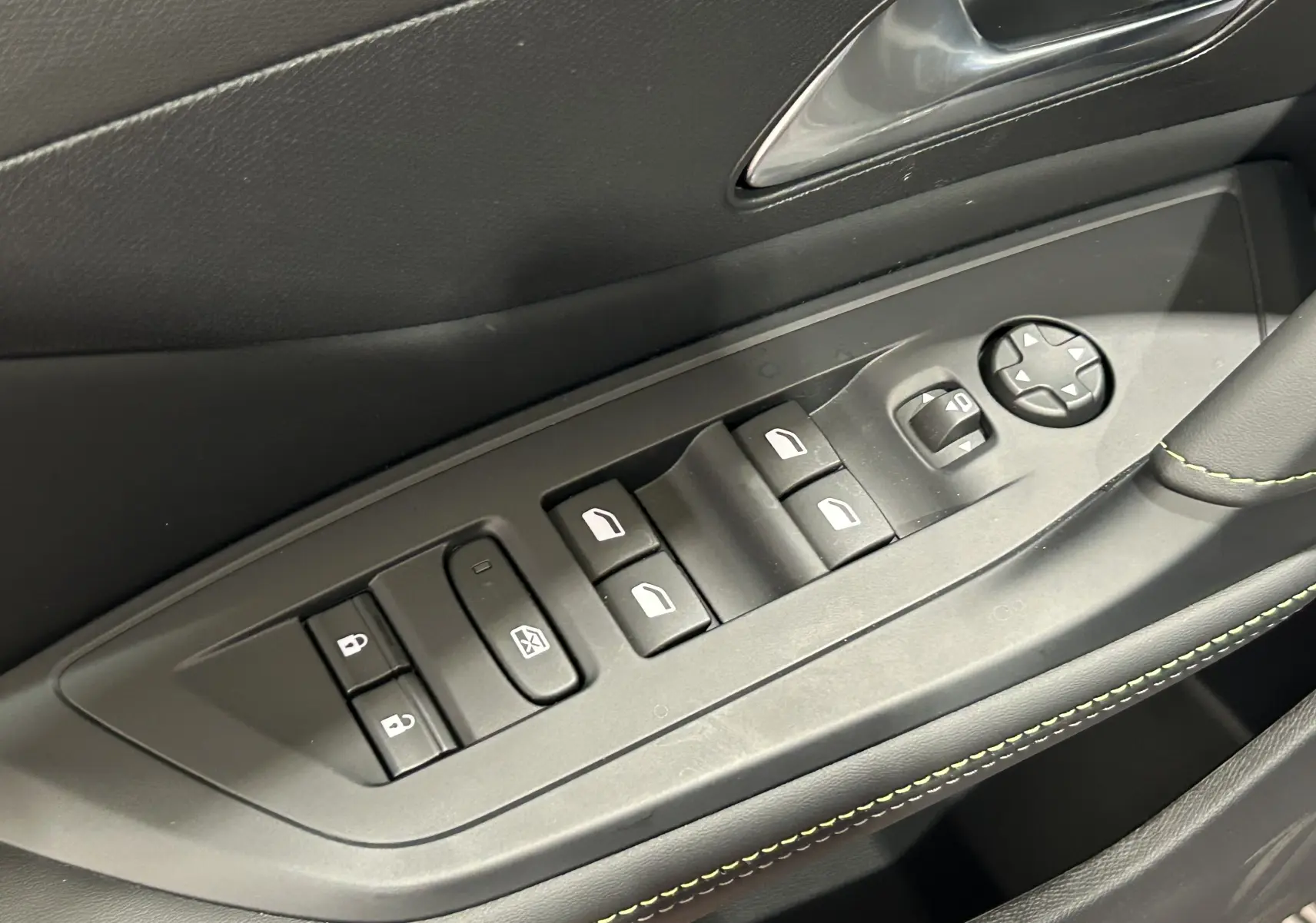 Gros plan sur les commandes de lève-vitres et rétroviseurs côté gauche intérieur d’une Peugeot 308 gris Artense.
