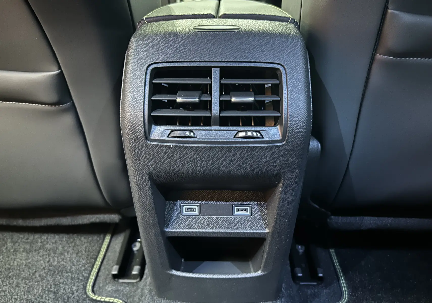 Vue rapprochée des aérateurs arrière et ports USB noirs sur la console centrale du Peugeot 308 gris Artense 2026.