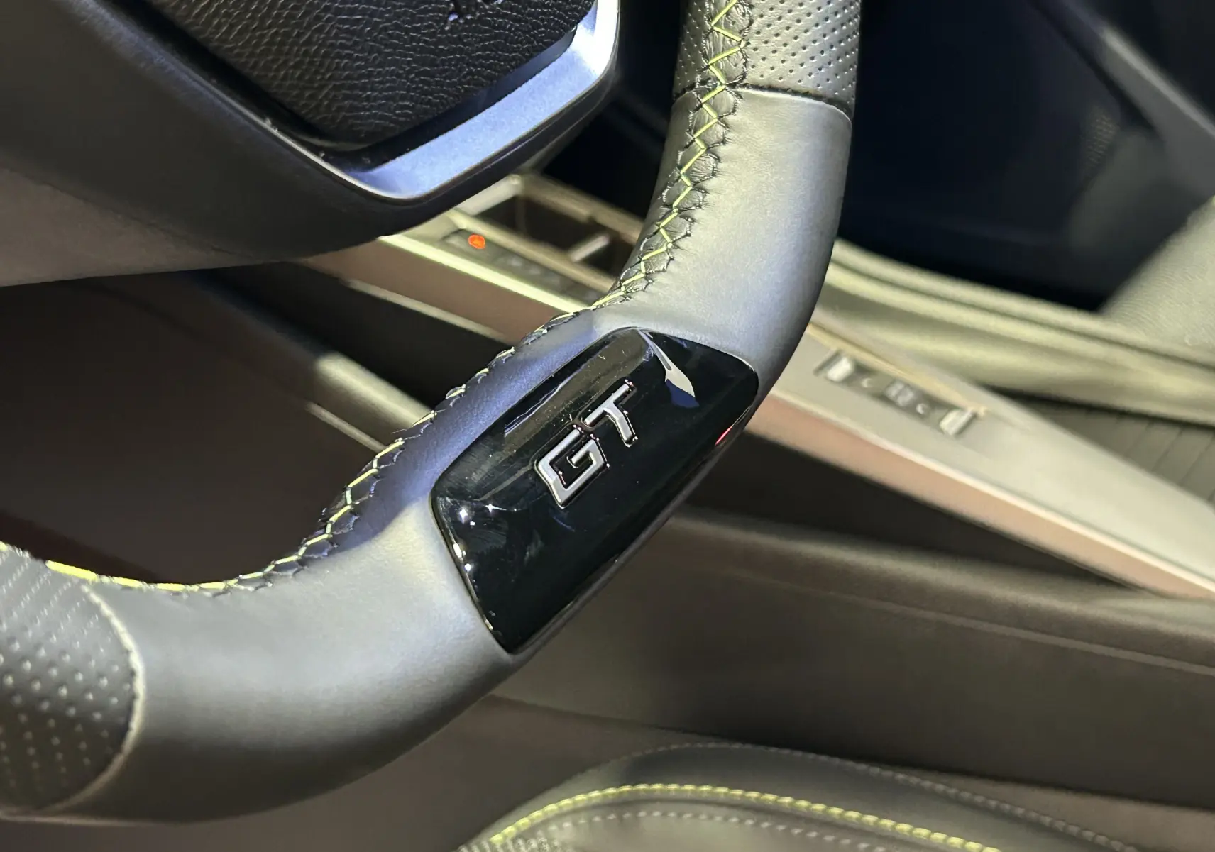 Gros plan sur le volant cuir gris avec logo GT de la Peugeot 308 III Ph.2 GT, intérieur moderne et finition soignée.