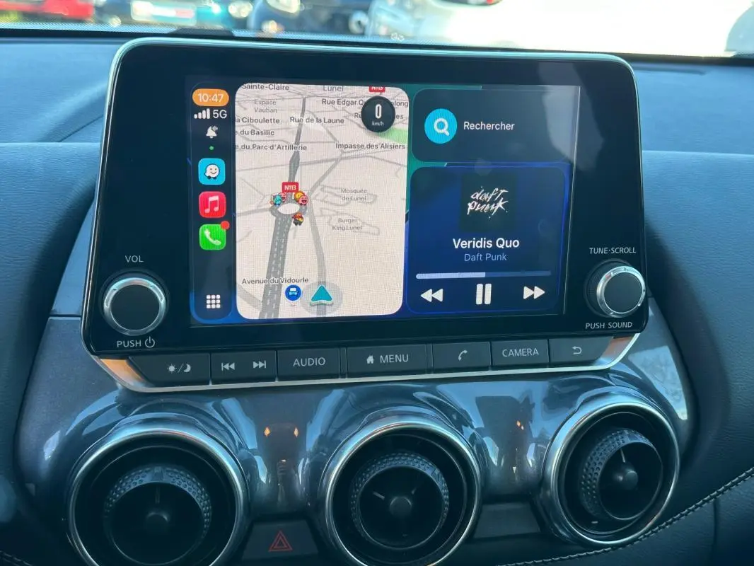 Écran tactile central du Nissan Juke 2023.5 DIG-T 114 Shadow avec navigation et musique, intérieur noir.