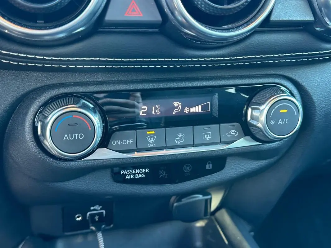 Gros plan sur la console de climatisation automatique du Nissan Juke 2023.5 bleu clair avec affichage digital et commandes rotatives.