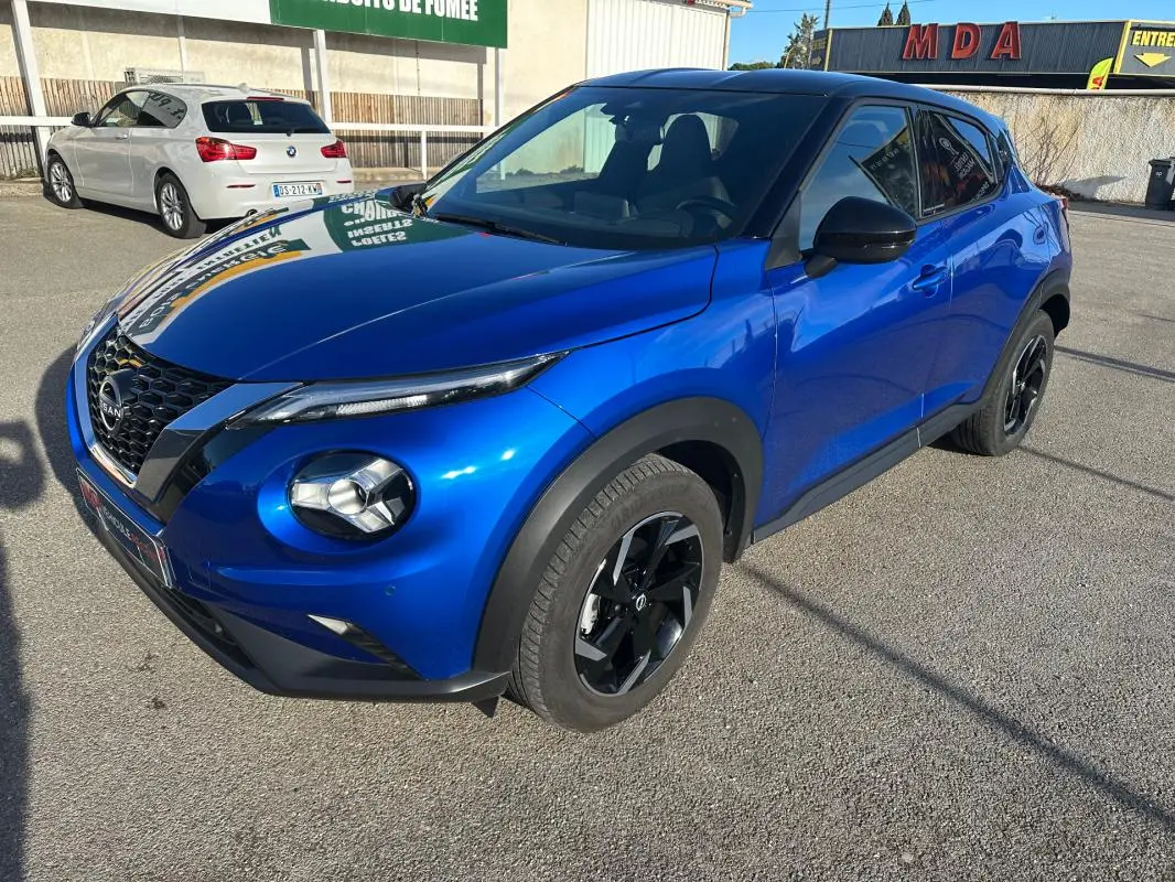 Nissan Juke 2024 bleu clair vu en 3/4 avant droit, avec jantes alliage noires et calandre distinctive V-Motion.