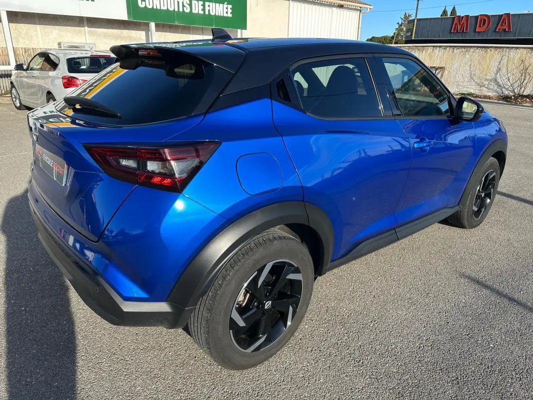 Vue 3/4 arrière droite du Nissan Juke 2024 bleu clair avec jantes alliage noires de 17 pouces et toit noir contrasté.