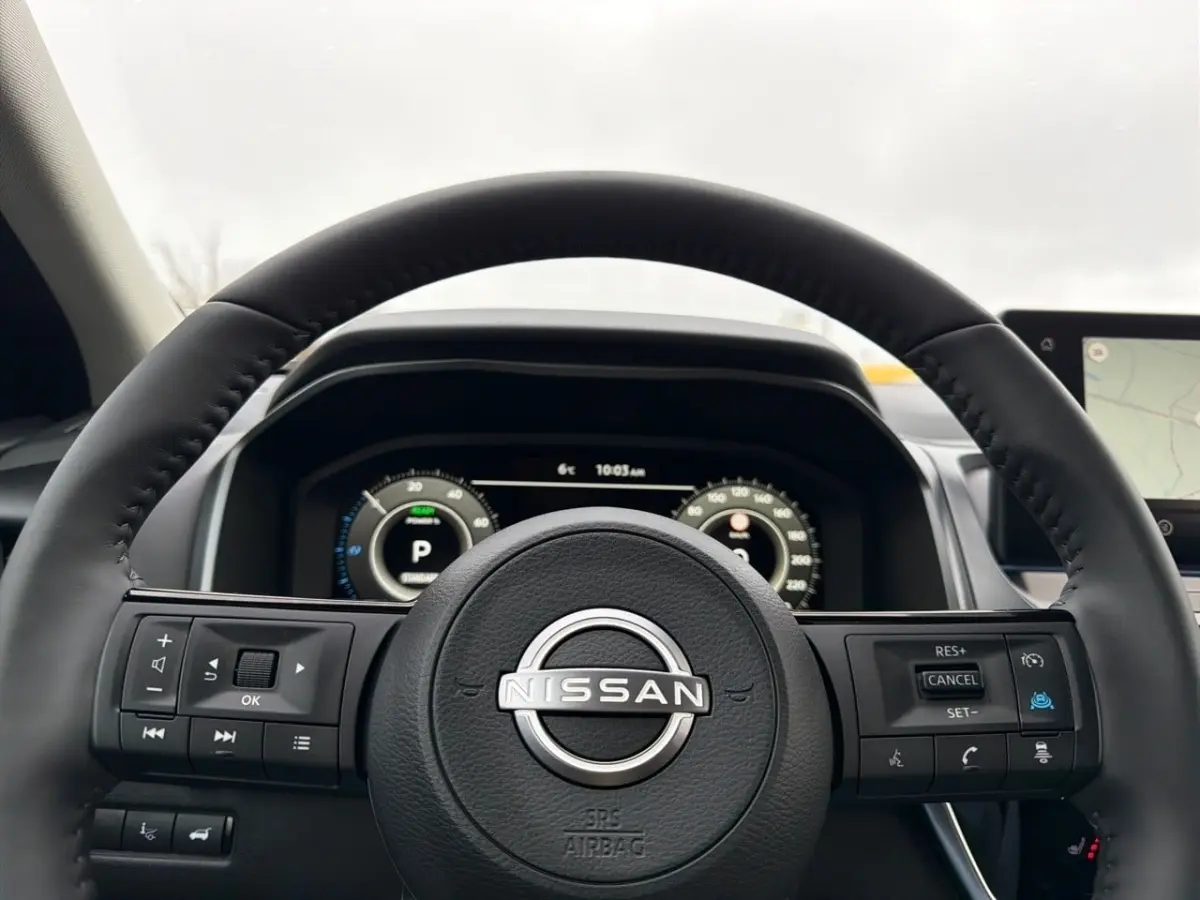 Vue rapprochée du volant cuir noir Nissan Qashqai 1.5 e-Power avec commandes multifonctions et tableau de bord numérique.