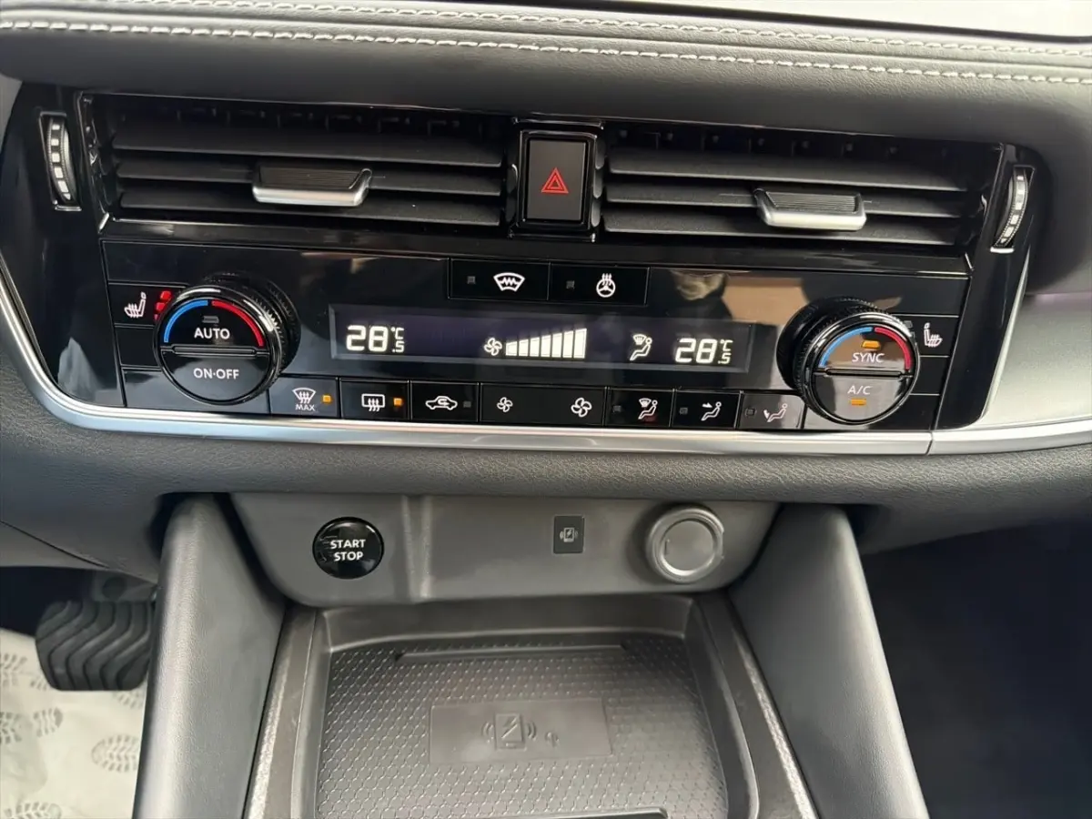 Vue rapprochée du tableau de bord noir du Nissan Qashqai 2025, avec commandes climatisation et bouton démarrage visible.