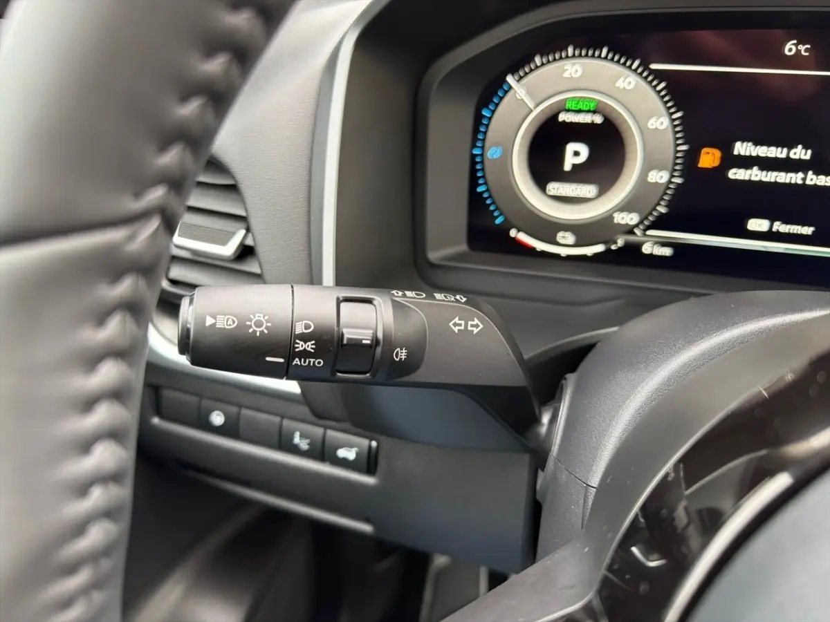 Gros plan sur le combiné d'instruments numérique et la commande des phares du Nissan Qashqai 1.5 e-Power noir, intérieur moderne.