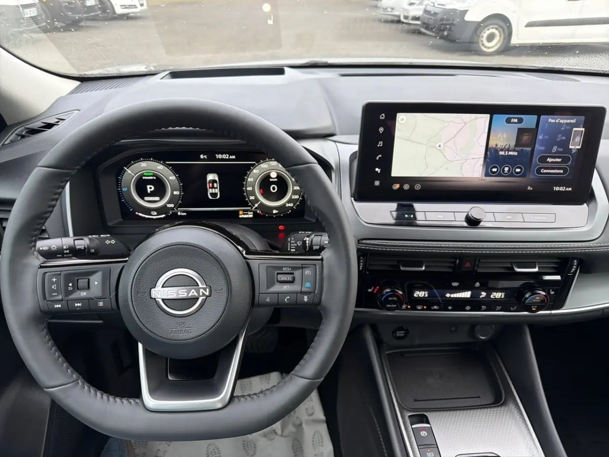 Vue intérieure du tableau de bord du Nissan Qashqai 1.5 e-Power 2025 avec écran tactile et volant multifonctions noir.