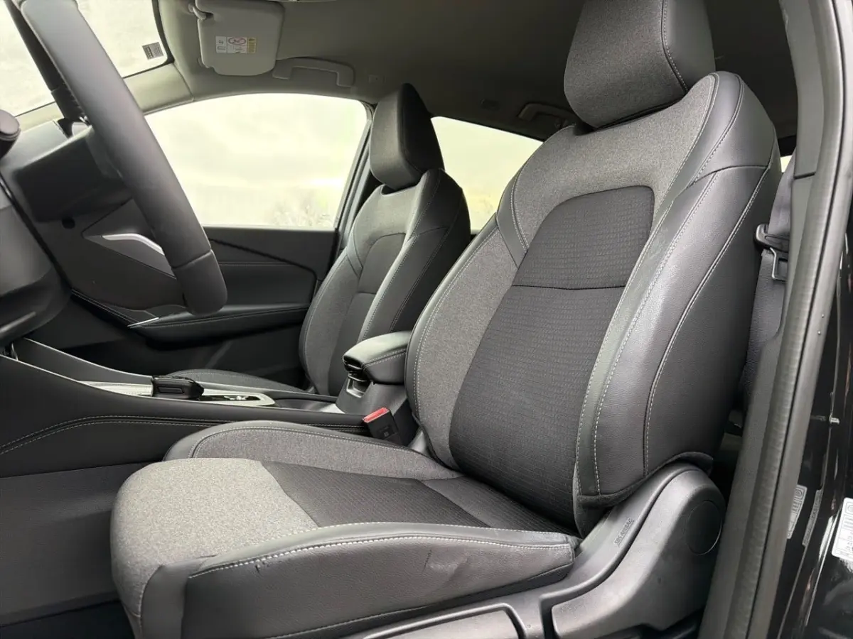 Vue intérieure côté conducteur du Nissan Qashqai noir 2025, mettant en valeur les sièges en tissu et cuir gris et noir.