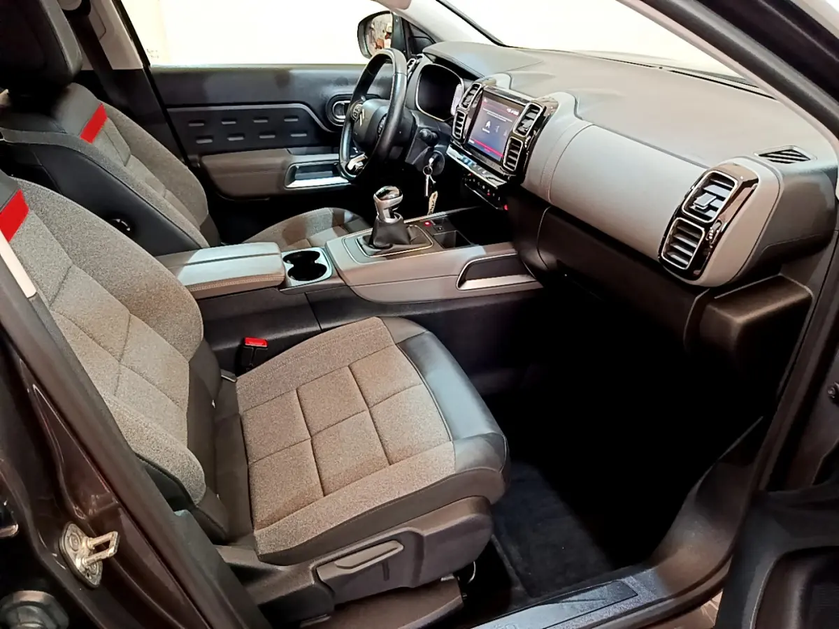 Intérieur avant droit du Citroën C5 Aircross gris foncé, sièges tissu gris et cuir noir, console centrale avec boîte manuelle.