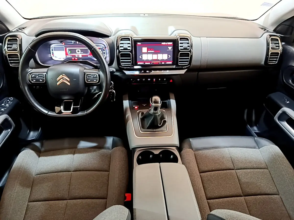 Vue intérieure avant du Citroën C5 Aircross 2020 montrant tableau de bord, volant cuir, écran tactile et sièges tissu gris.