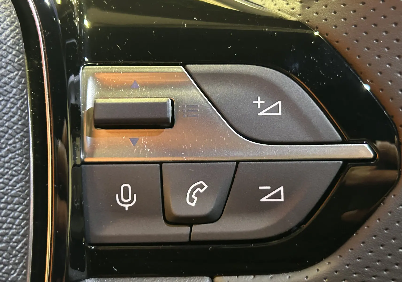 Gros plan sur les commandes noires du volant du Peugeot 308 III Ph.2 Hybrid 145 GT en gris Selenium.