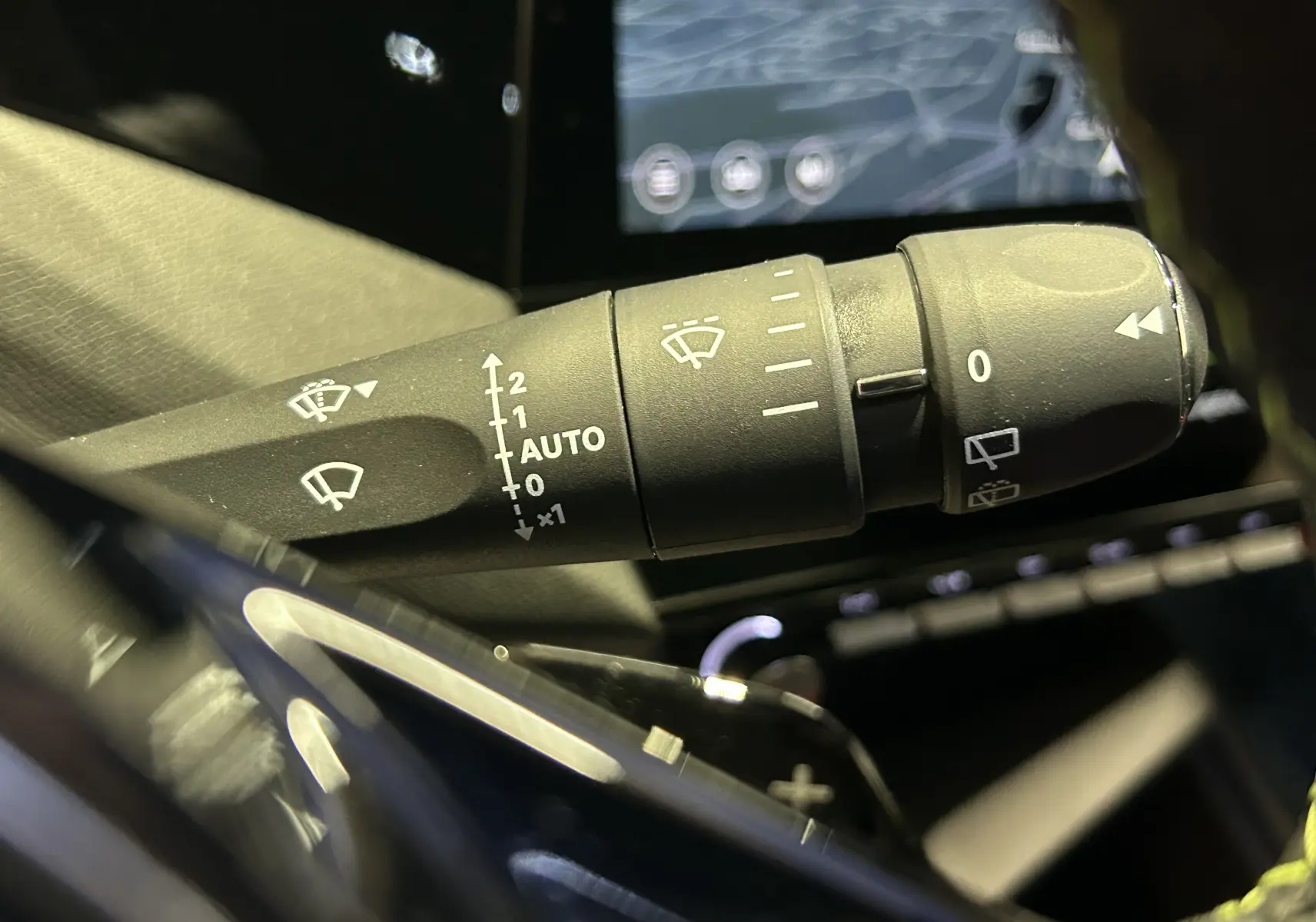 Gros plan sur la commande des essuie-glaces dans l’habitacle de la Peugeot 308 gris Selenium, avec écran tactile en arrière-plan.