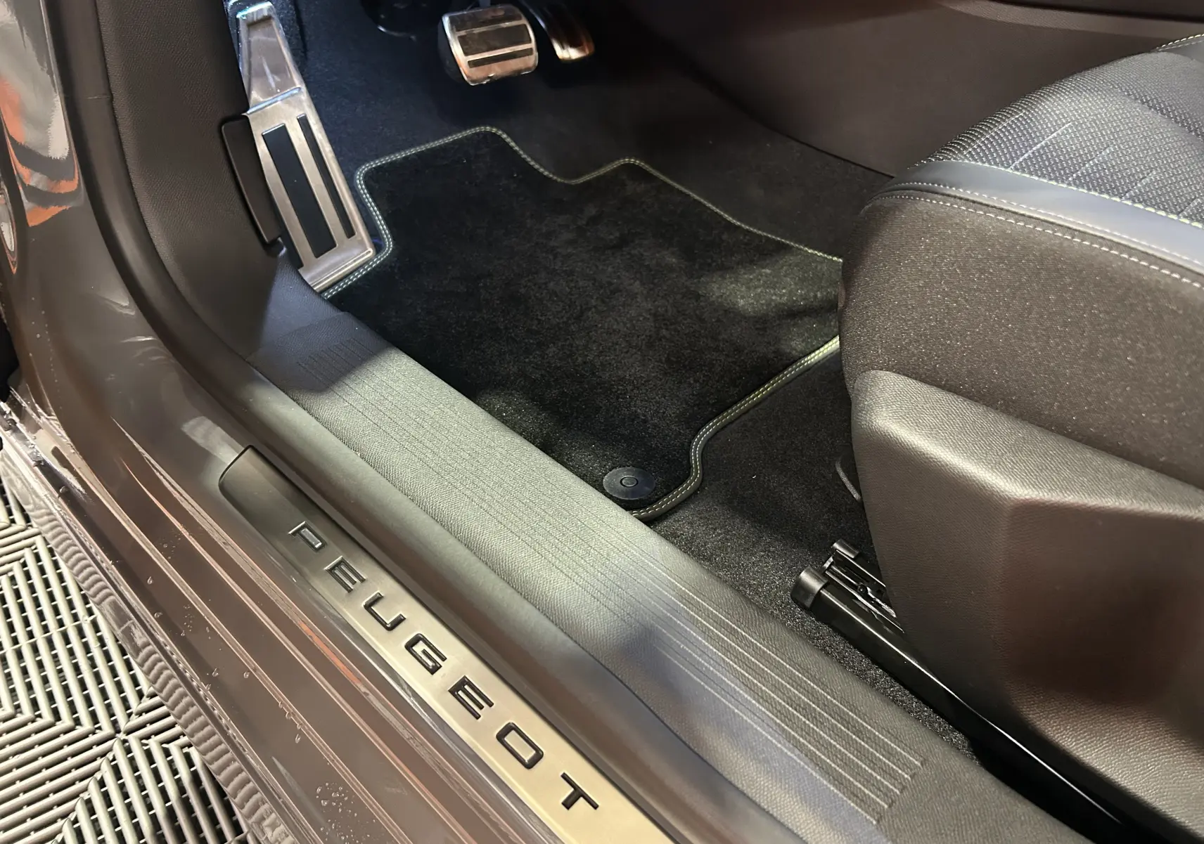 Vue rapprochée de la partie basse côté gauche d’une Peugeot 308 gris Selenium avec seuil de porte marqué PEUGEOT.