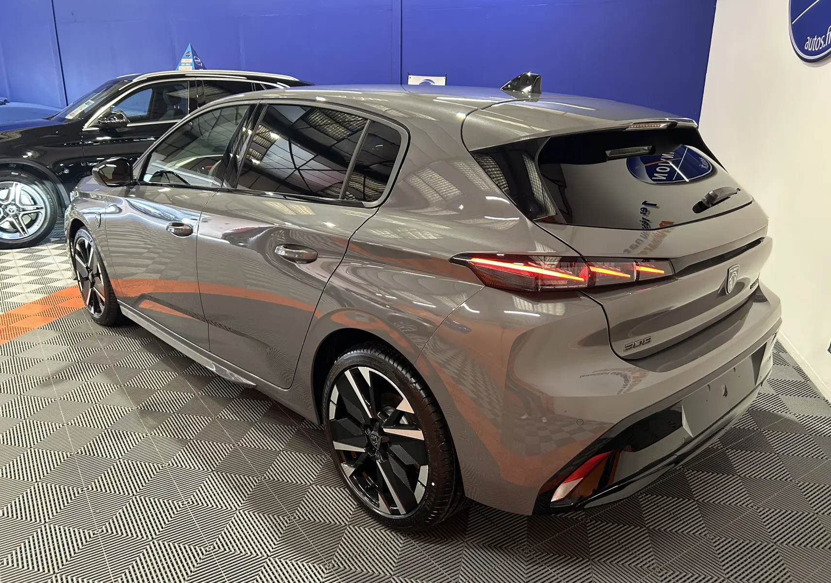 Vue 3/4 arrière droite d’une Peugeot 308 gris Selenium avec feux LED allumés et jantes noires bicolores.