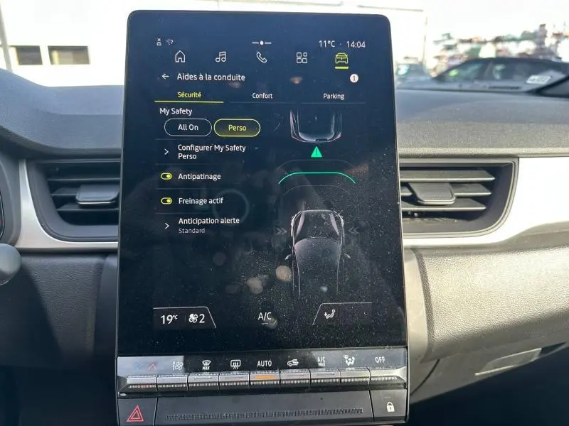 Écran tactile central du tableau de bord du Renault Captur 2025 affichant les aides à la conduite et la climatisation.