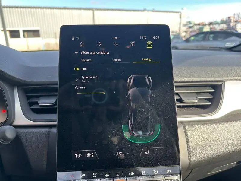 Vue du tableau de bord du Renault Captur 2025, écran tactile central affichant l'aide au stationnement.