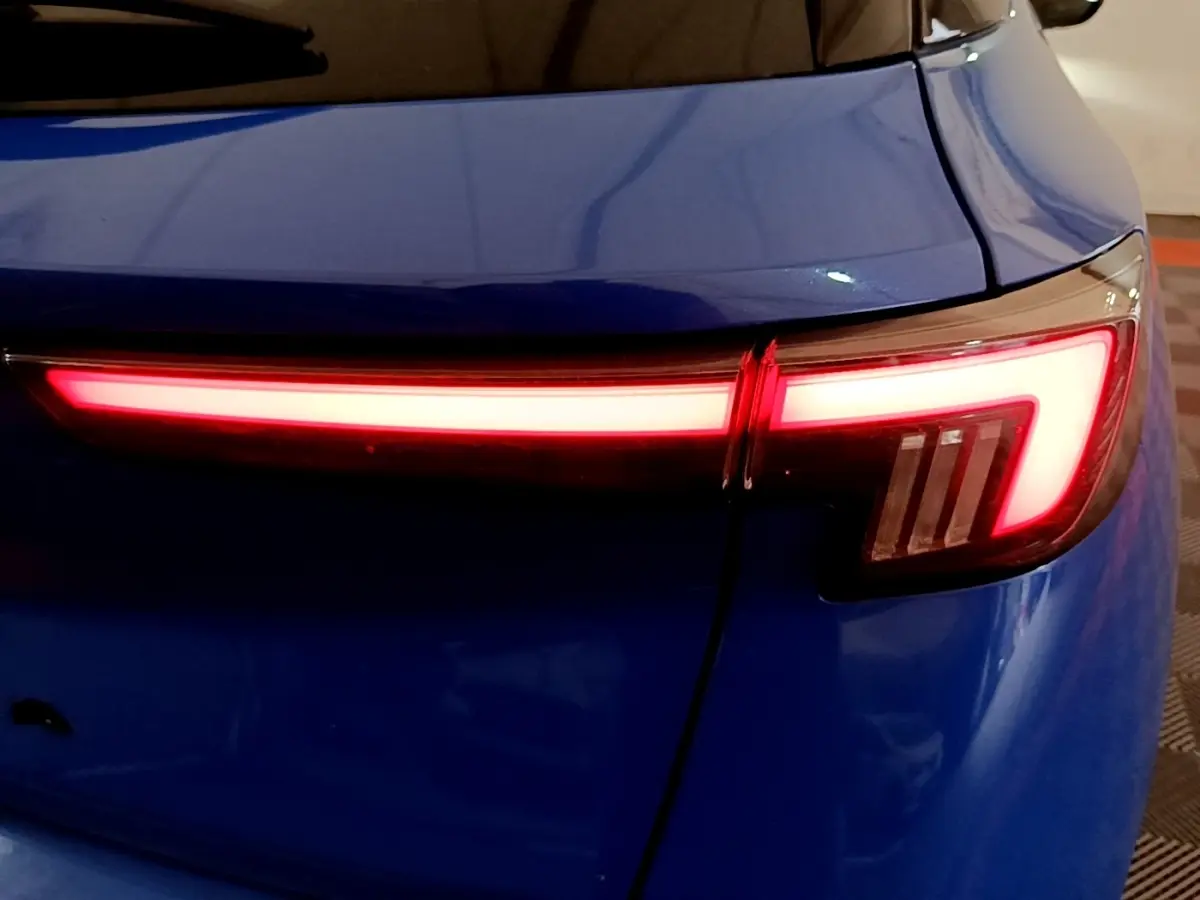 Feu arrière droit allumé sur Opel Mokka bleu, vue rapprochée du coffre et de la lunette arrière.