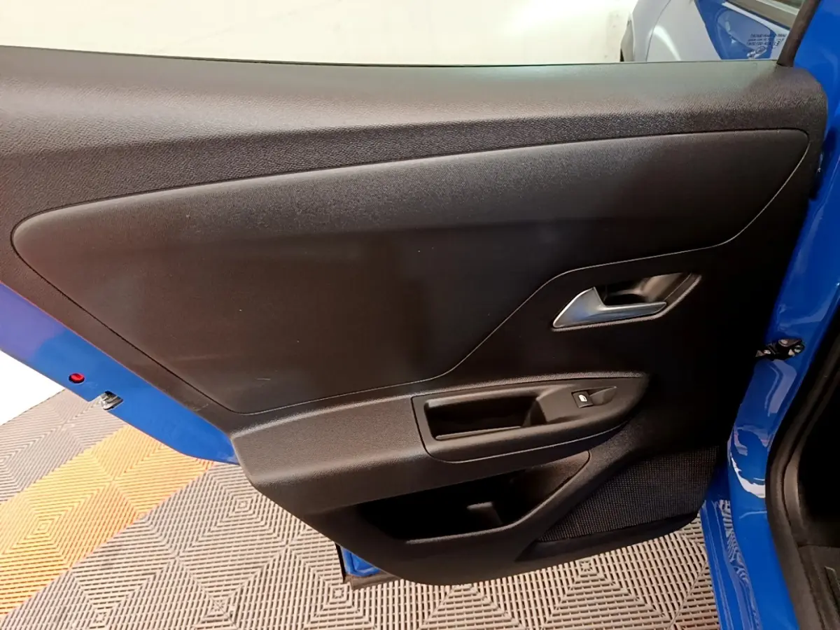 Vue rapprochée de la porte arrière gauche noire avec poignée argentée sur Opel Mokka bleu 2024.
