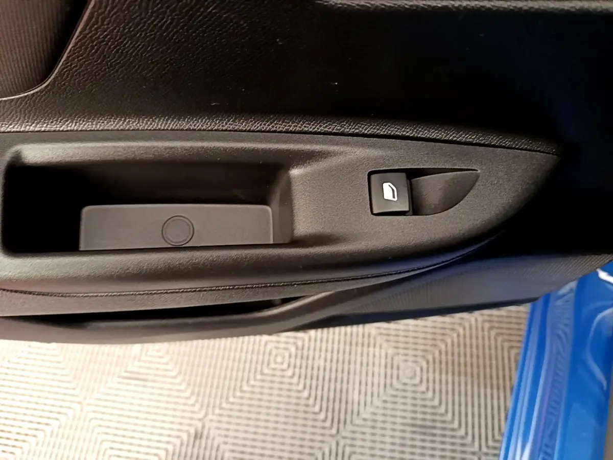 Détail de la commande de lève-vitre sur la porte côté conducteur d’un Opel Mokka bleu 2024.