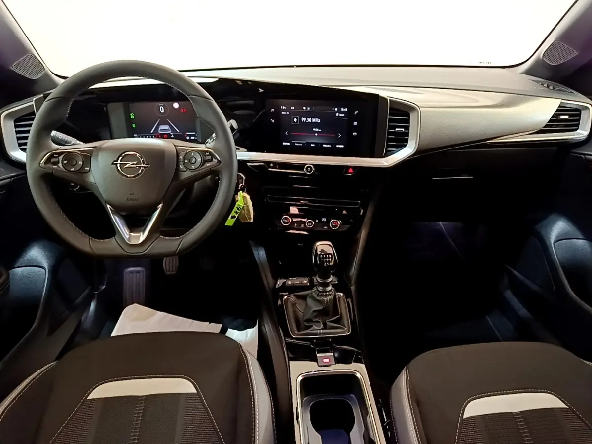 Vue intérieure avant de l’Opel Mokka 2024, tableau de bord noir avec écran tactile et volant multifonctions cuir.