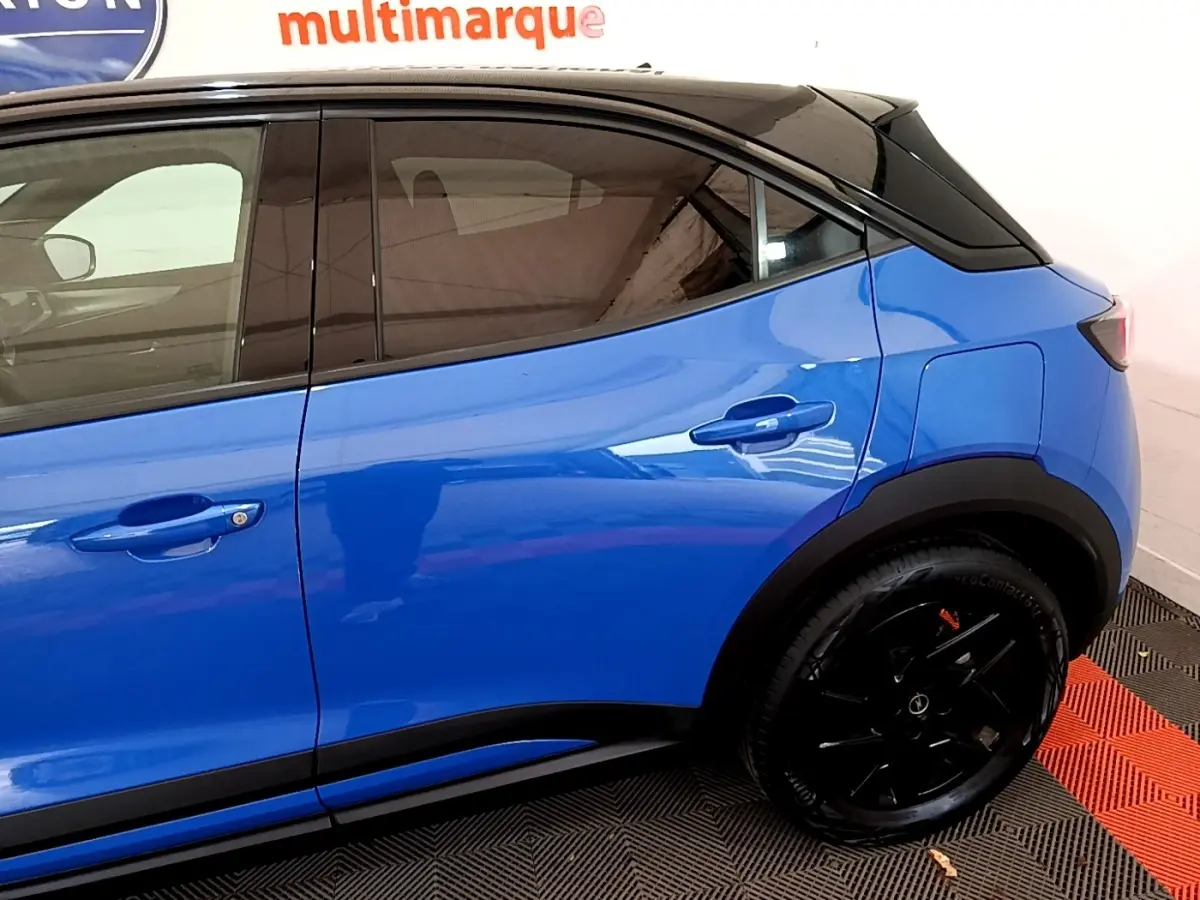 Vue latérale droite d'un Opel Mokka bleu 2024 avec toit noir et jantes noires brillantes.