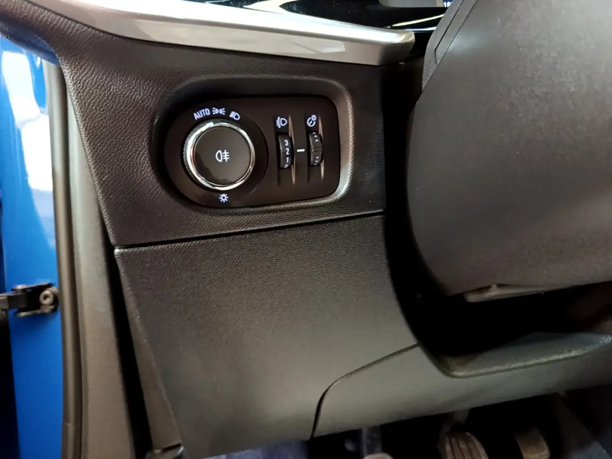 Gros plan sur le panneau de commande des feux à gauche du volant dans l’habitacle bleu d’un Opel Mokka 2024.