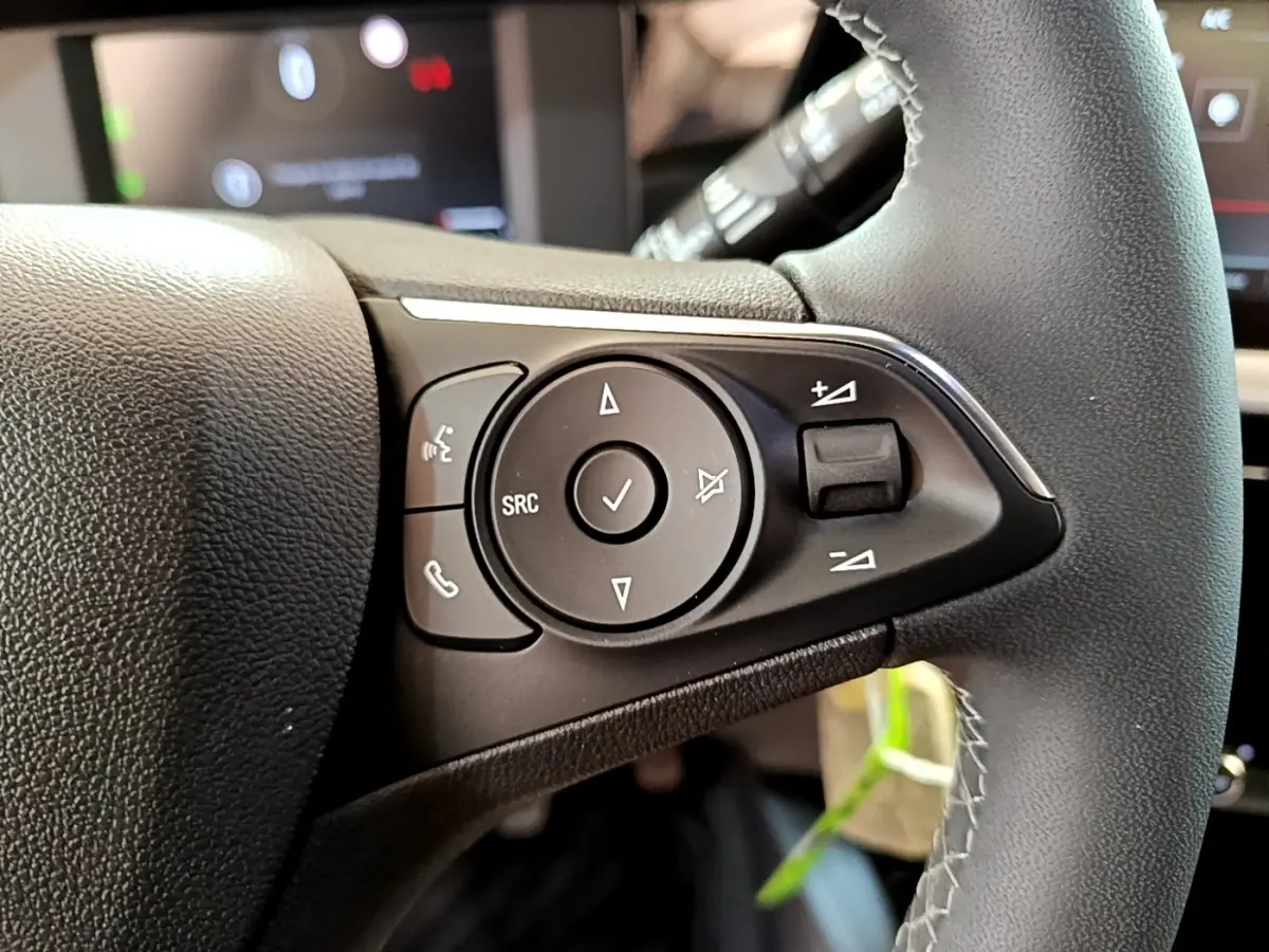 Gros plan sur les commandes multifonctions du volant en cuir noir de l'Opel Mokka 2024, version essence.