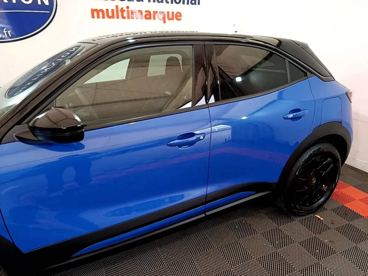 Profil droit d’un Opel Mokka 2024 bleu avec toit et rétroviseur noirs, jantes noires et poignées couleur carrosserie.